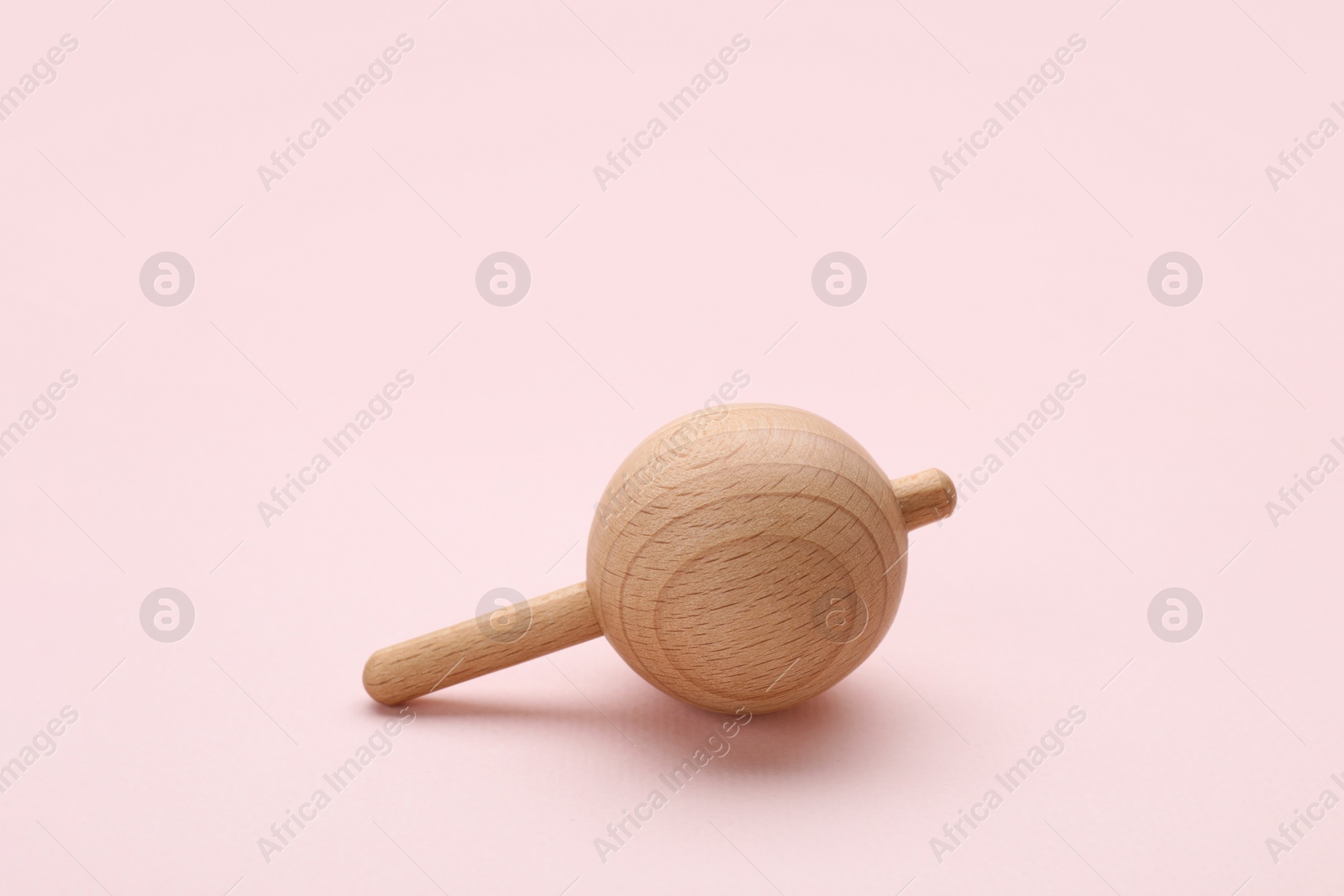 Photo of One wooden spinning top on beige background, space for text. Toy whirligig