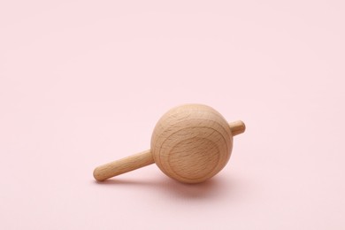 Photo of One wooden spinning top on beige background, space for text. Toy whirligig
