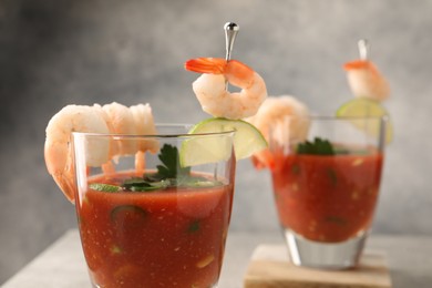 Photo of Tasty shrimp cocktail with sauce in glasses and lime on table, closeup