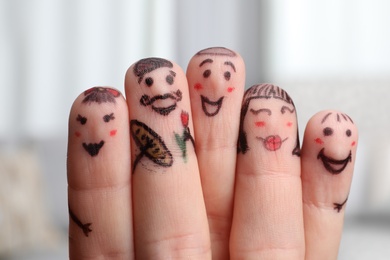 Photo of Five fingers with drawings of happy faces on blurred background