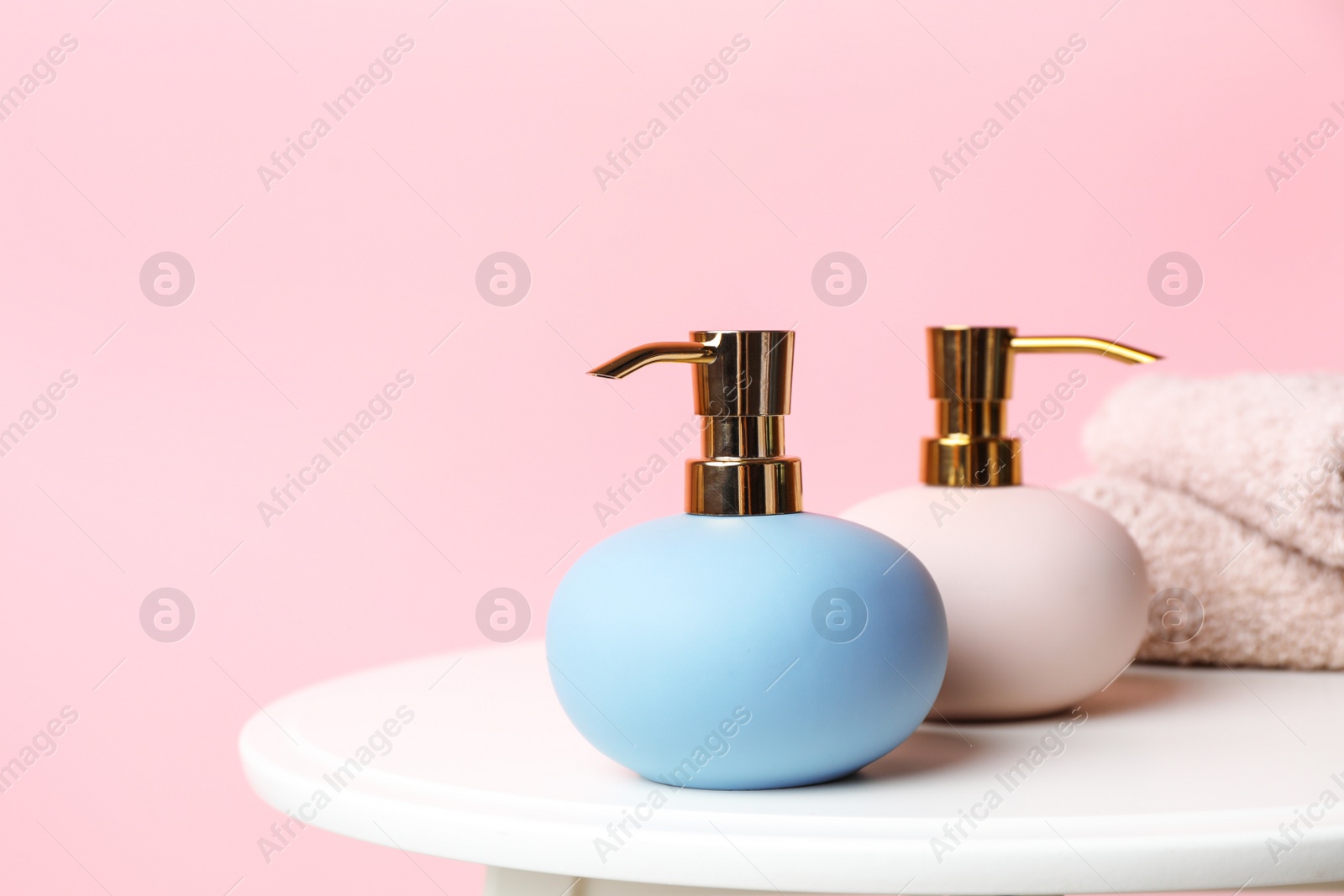 Photo of Stylish soap dispensers on table against color background. Space for text