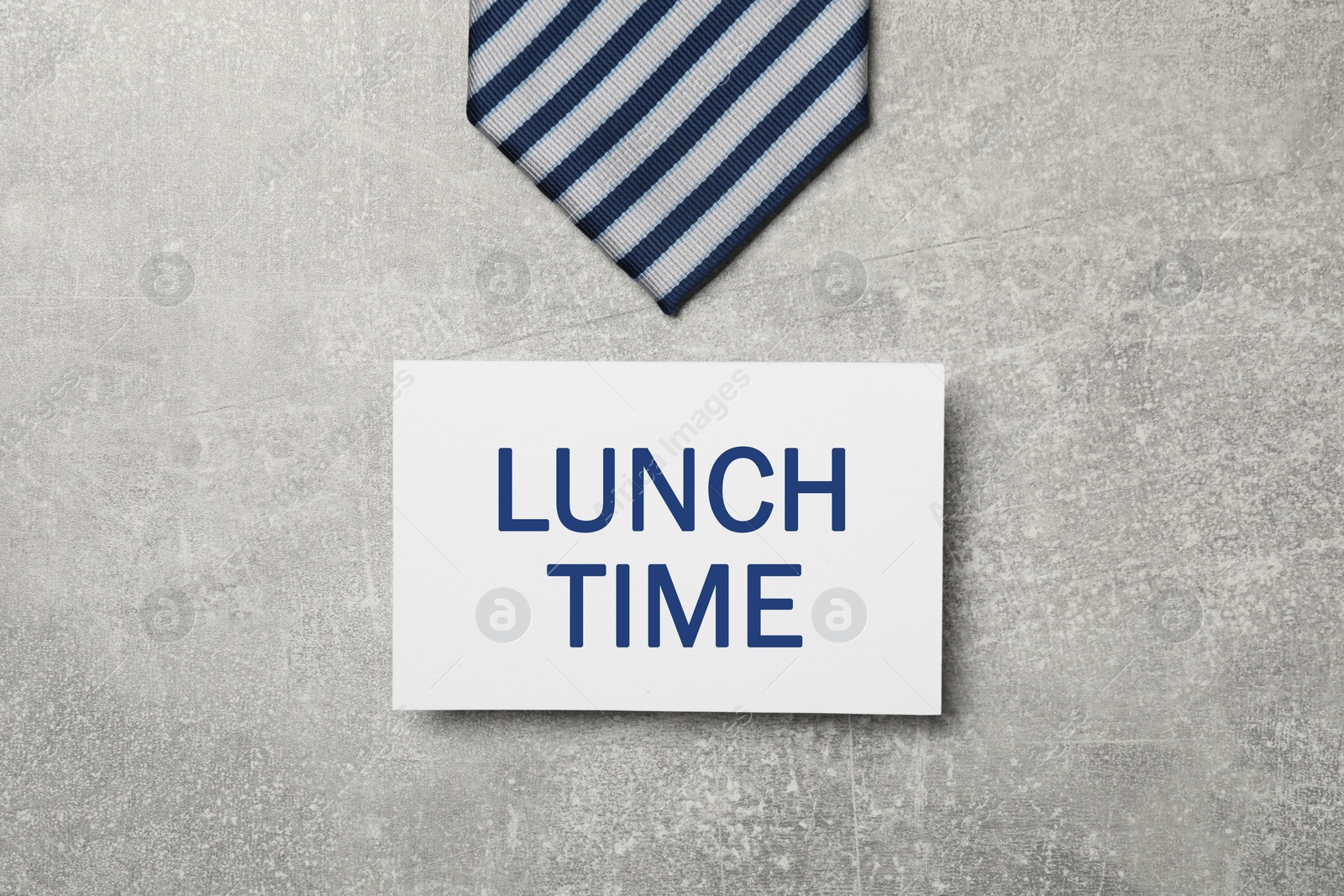 Image of Business lunch. Card with phrase Lunch Time and striped tie on light gray textured background, flat lay