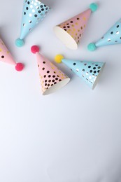 Photo of Beautiful party hats with pompoms on light background, top view. Space for text