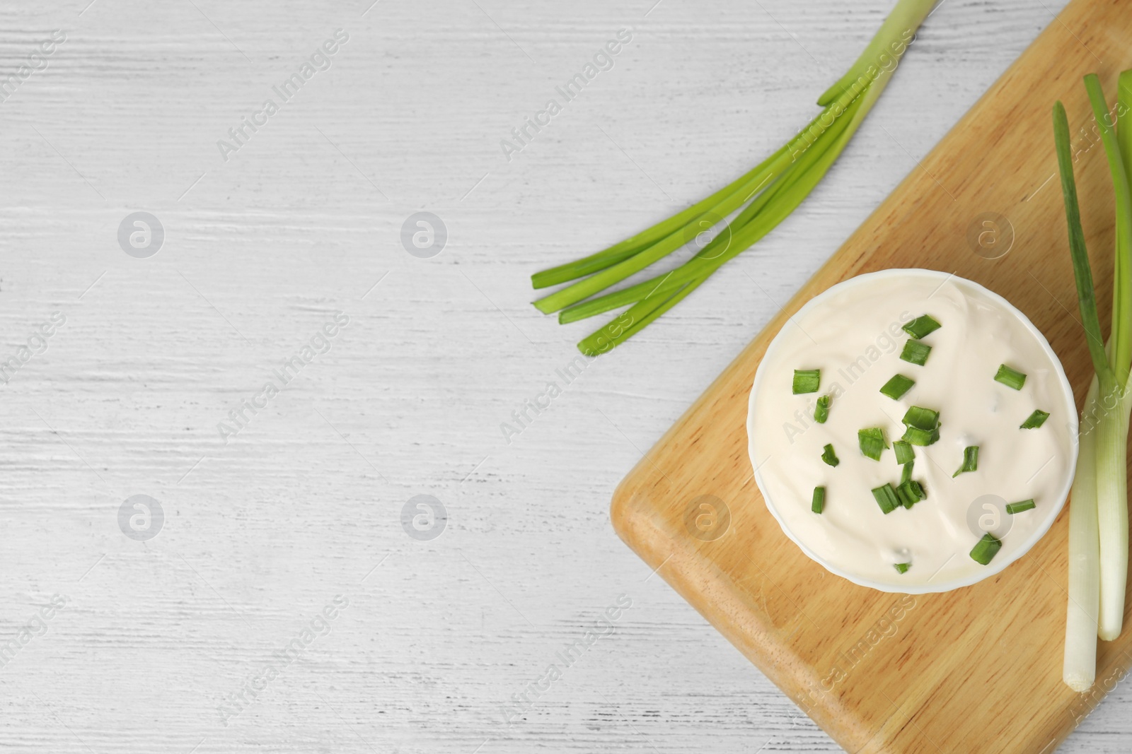 Photo of Fresh sour cream with onion on white wooden table, flat lay. Space for text