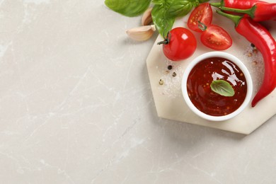 Photo of Spicy chili sauce and ingredients on light table, flat lay. Space for text