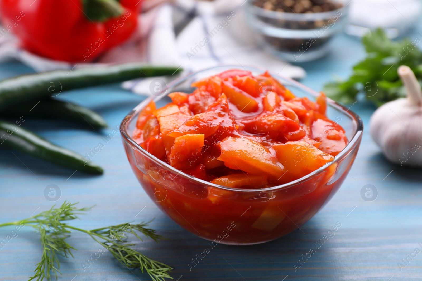 Photo of Bowl of delicious lecho on light blue wooden table, closeup