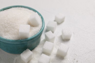 Different types of sugar in bowl on white table, closeup. Space for text