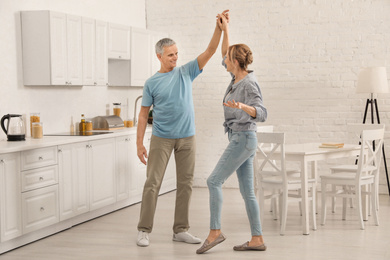 Happy senior couple dancing together in kitchen