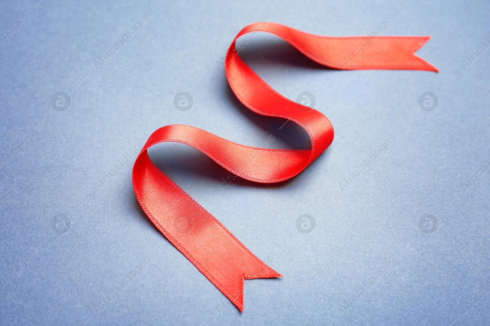 Photo of Simple red ribbon on color background. Festive decoration