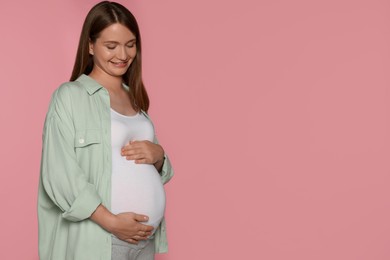 Photo of Happy pregnant woman on pink background. Space for text