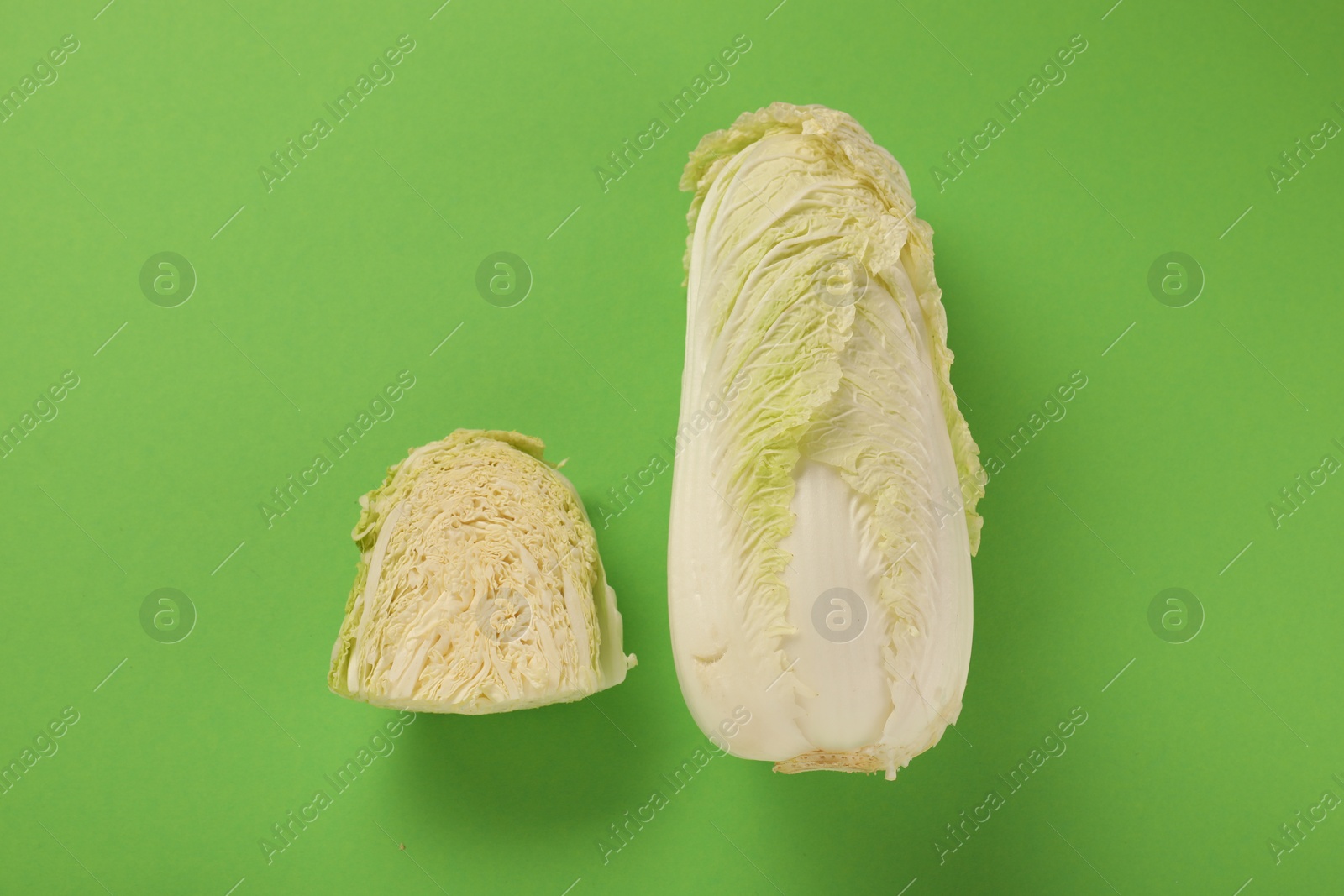 Photo of Whole and cut fresh Chinese cabbages on light green background, flat lay