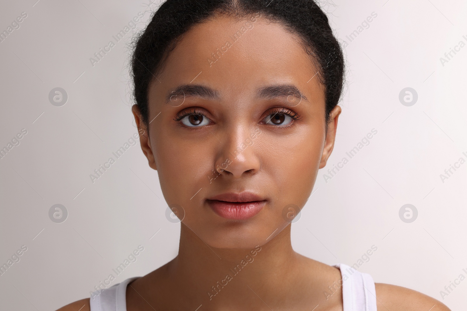Photo of Portrait of beautiful woman looking at camera on light background, closeup