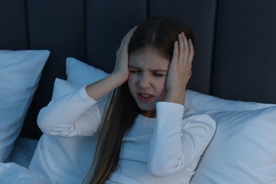 Little girl suffering from headache in bed at night