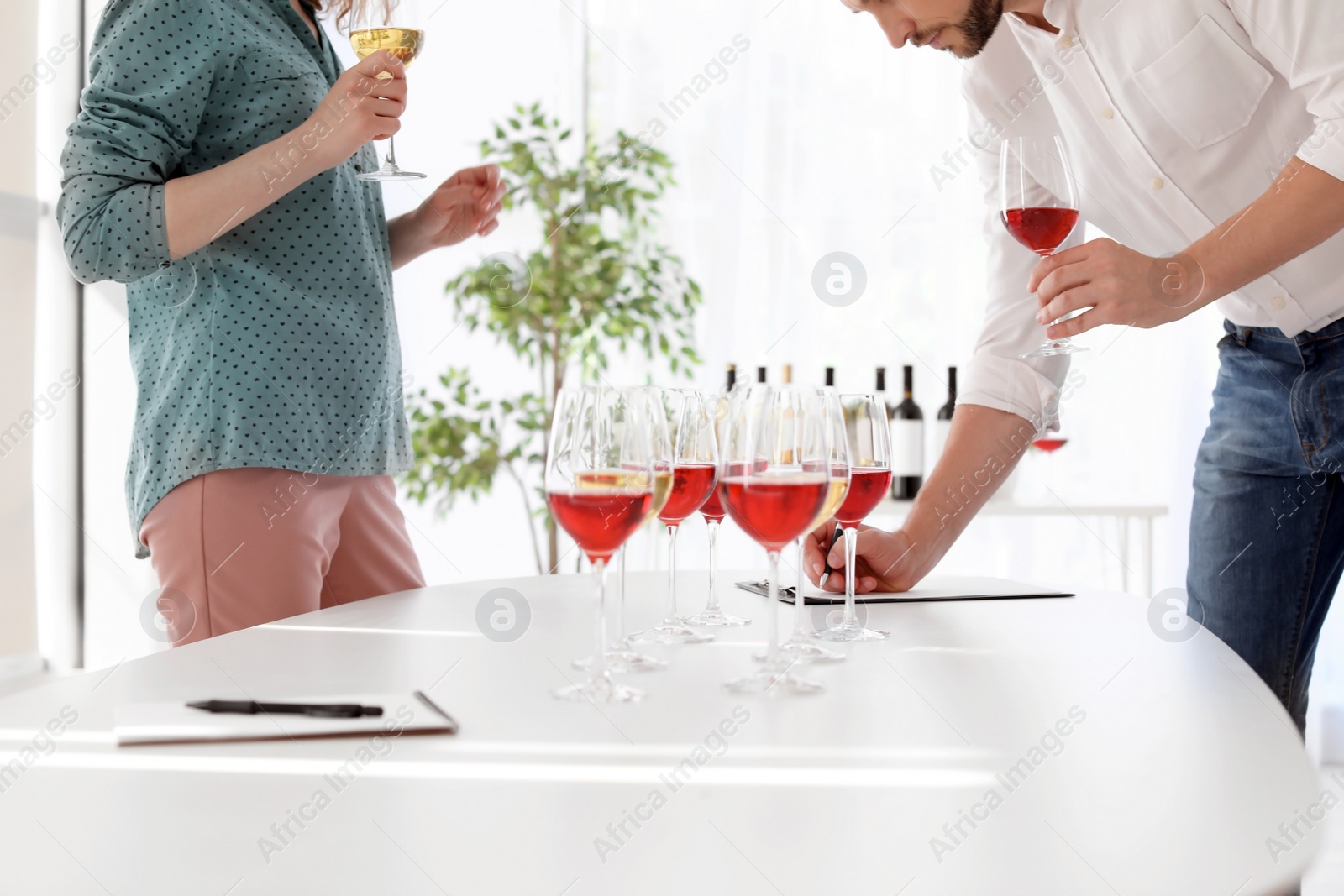 Photo of Young couple tasting wine at table indoors