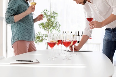 Young couple tasting wine at table indoors