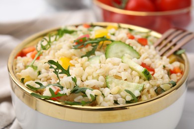 Cooked bulgur with vegetables in bowl, closeup