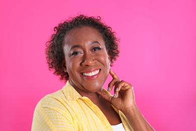 Portrait of happy African-American woman on pink background