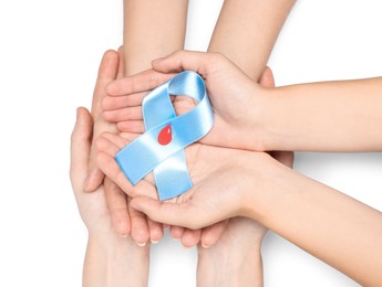 Photo of People holding light blue ribbon with paper blood drop on white background, top view. World Diabetes Day