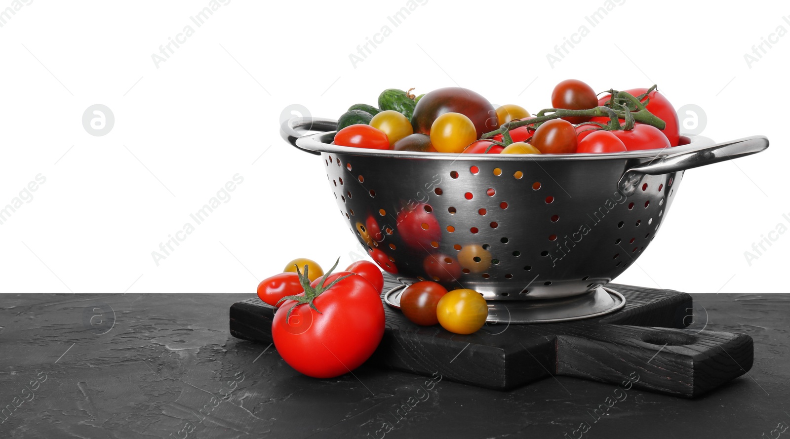 Photo of Metal colander with fresh tomatoes on black textured table against white background, space for text