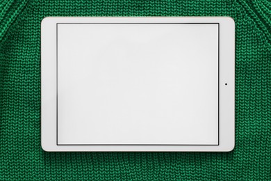 Modern tablet on green fabric, top view. Space for text