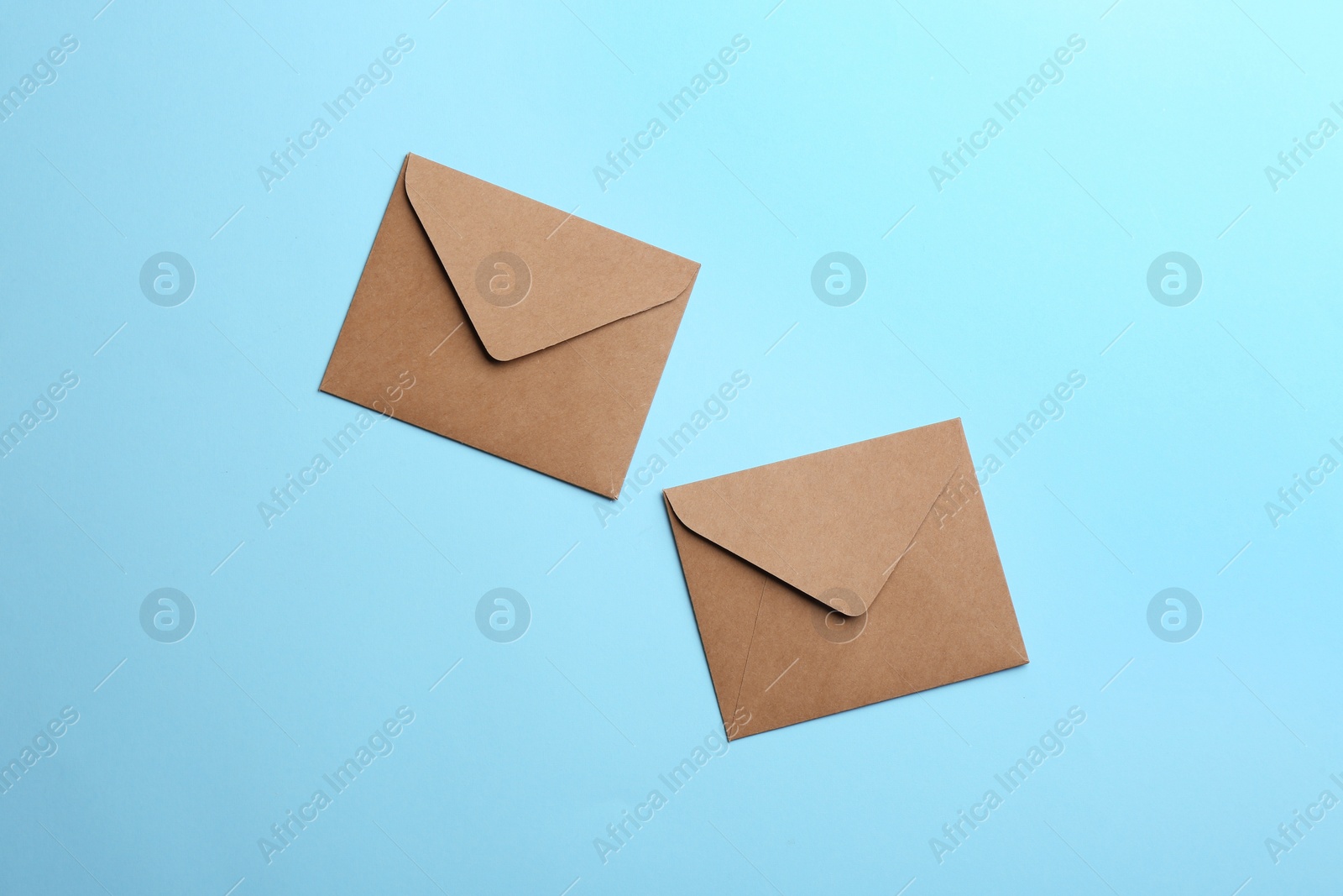 Photo of Brown paper envelopes on light blue background, flat lay