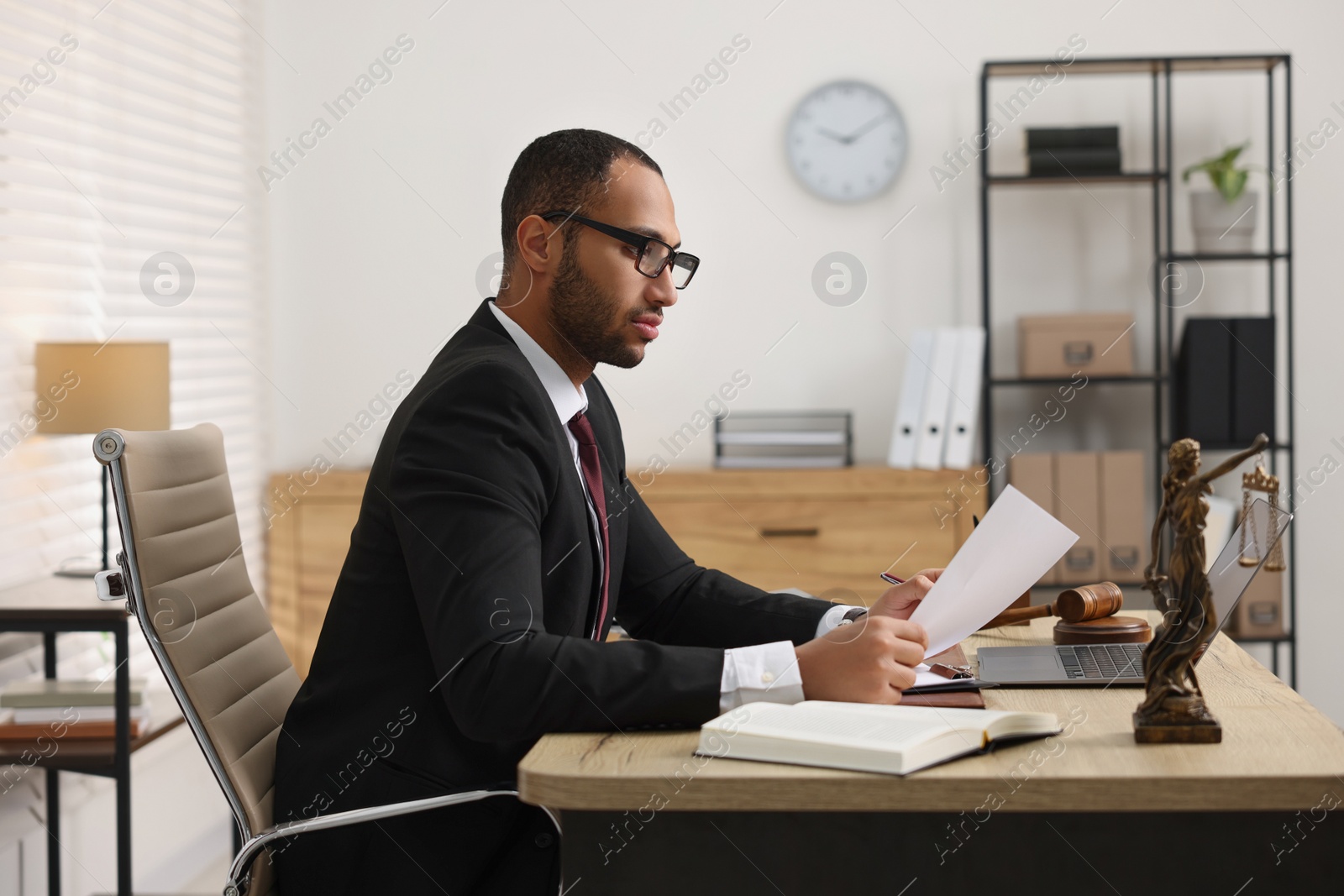 Photo of Confident lawyer working with document at table in office