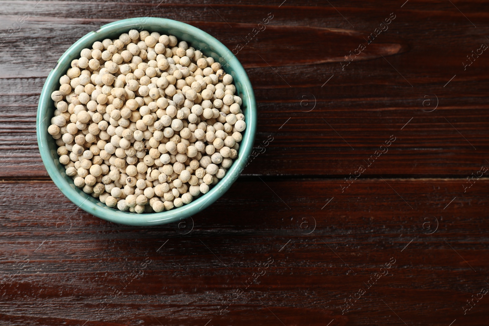 Photo of Aromatic spice. White pepper in bowl on wooden table, top view. Space for text