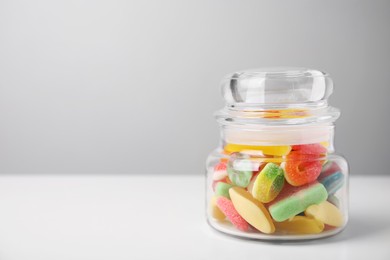 Photo of Tasty jelly candies in jar on white table, space for text