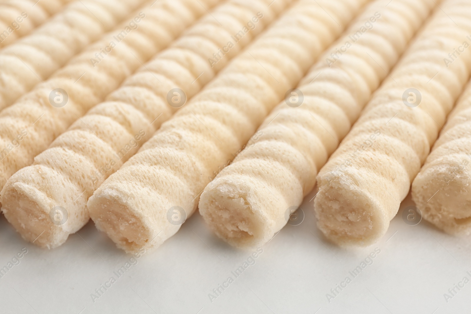 Photo of Delicious wafer rolls on white background, closeup. Sweet food