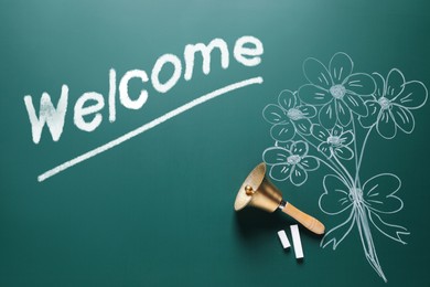 Image of Welcome card. Golden bell, chalk, word and drawn flowers on green board, flat lay