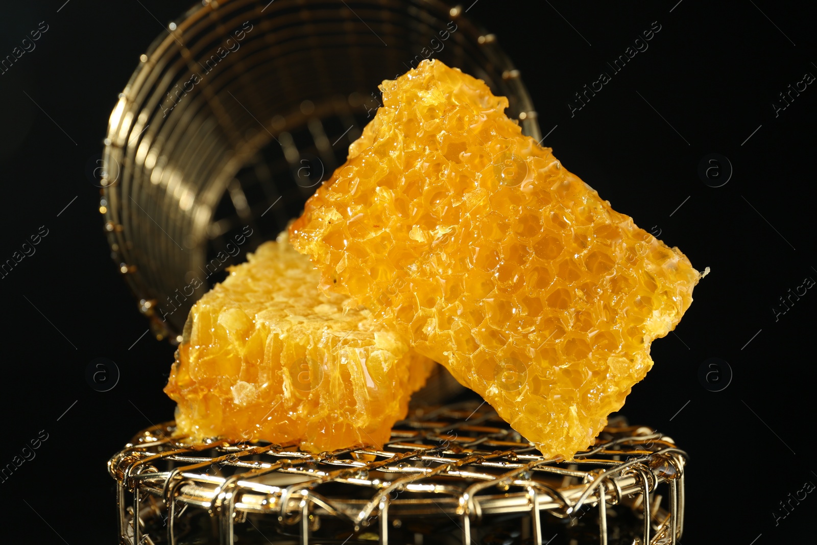 Photo of Natural honeycombs with tasty honey on black background, closeup