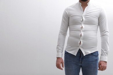Photo of Man wearing tight shirt on white background, closeup. Overweight problem