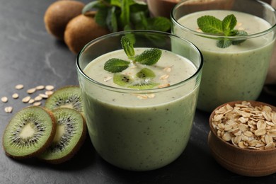 Glasses of tasty kiwi smoothie with oatmeal on dark table