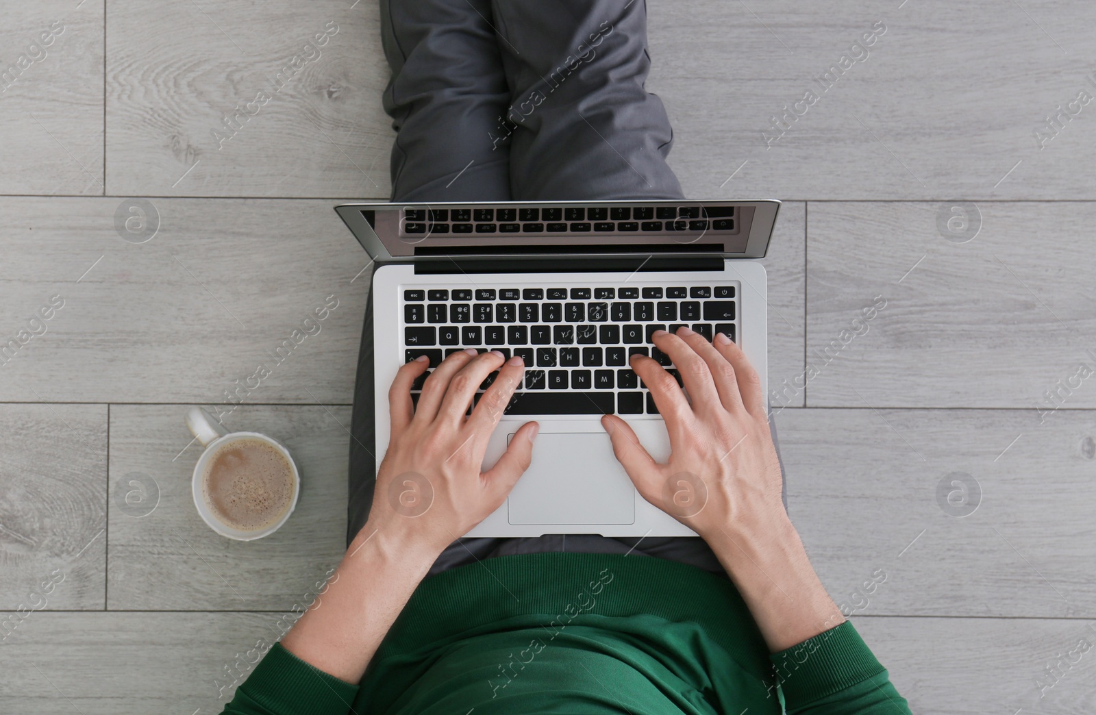 Photo of Young man using laptop while sitting on floor, top view