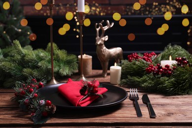 Photo of Plate with red fabric napkin, cutlery and festive decor on wooden table. Space for text
