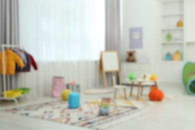 Photo of Blurred view of child`s playroom with different toys and furniture. Stylish kindergarten interior