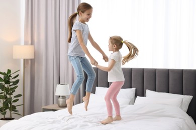 Photo of Cute little sisters having fun together on bed at home