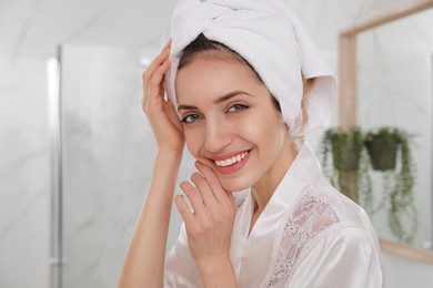 Photo of Beautiful young woman with hair wrapped in towel after washing at home