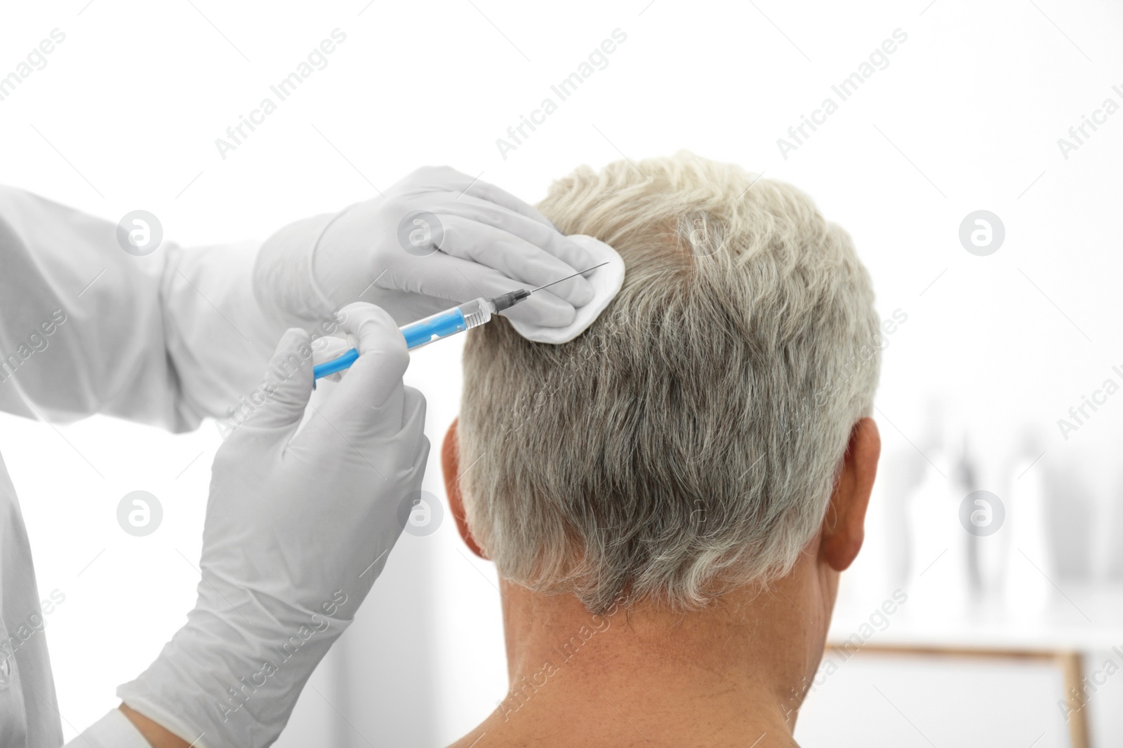 Photo of Senior man with hair loss problem receiving injection in salon