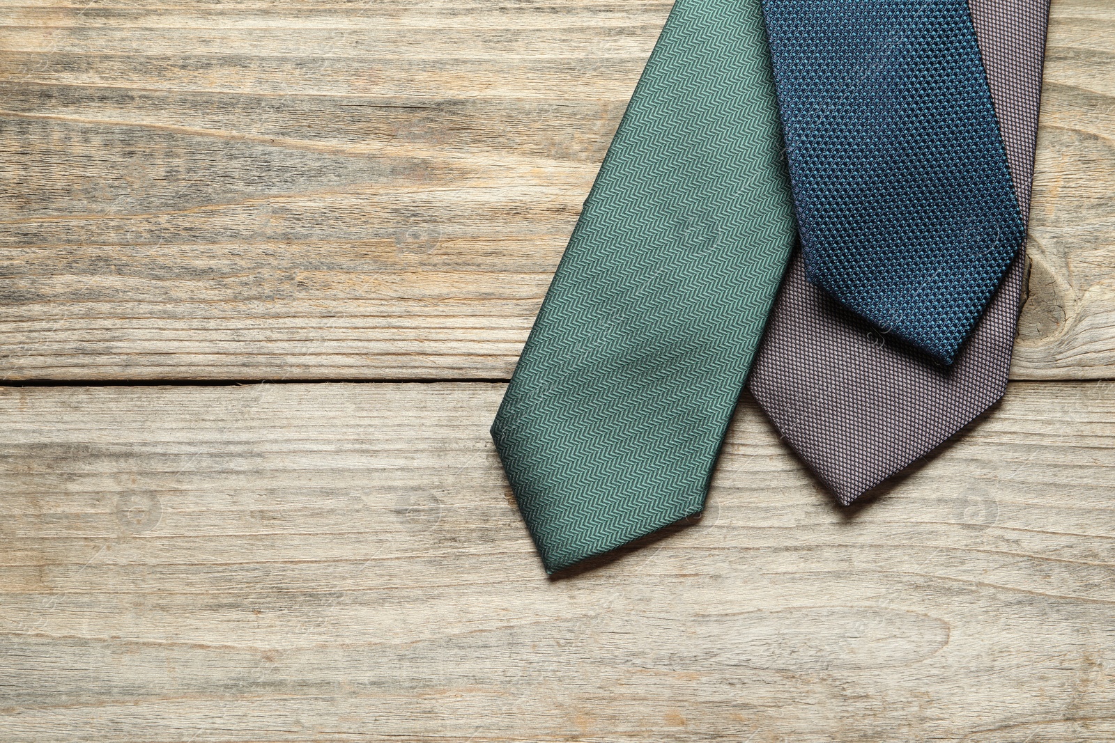 Photo of Different neckties on light wooden table, flat lay. Space for text