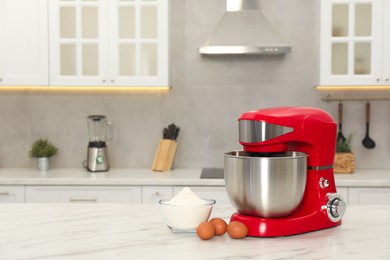 Modern red stand mixer, eggs and bowl with flour on white marble table in kitchen, space for text