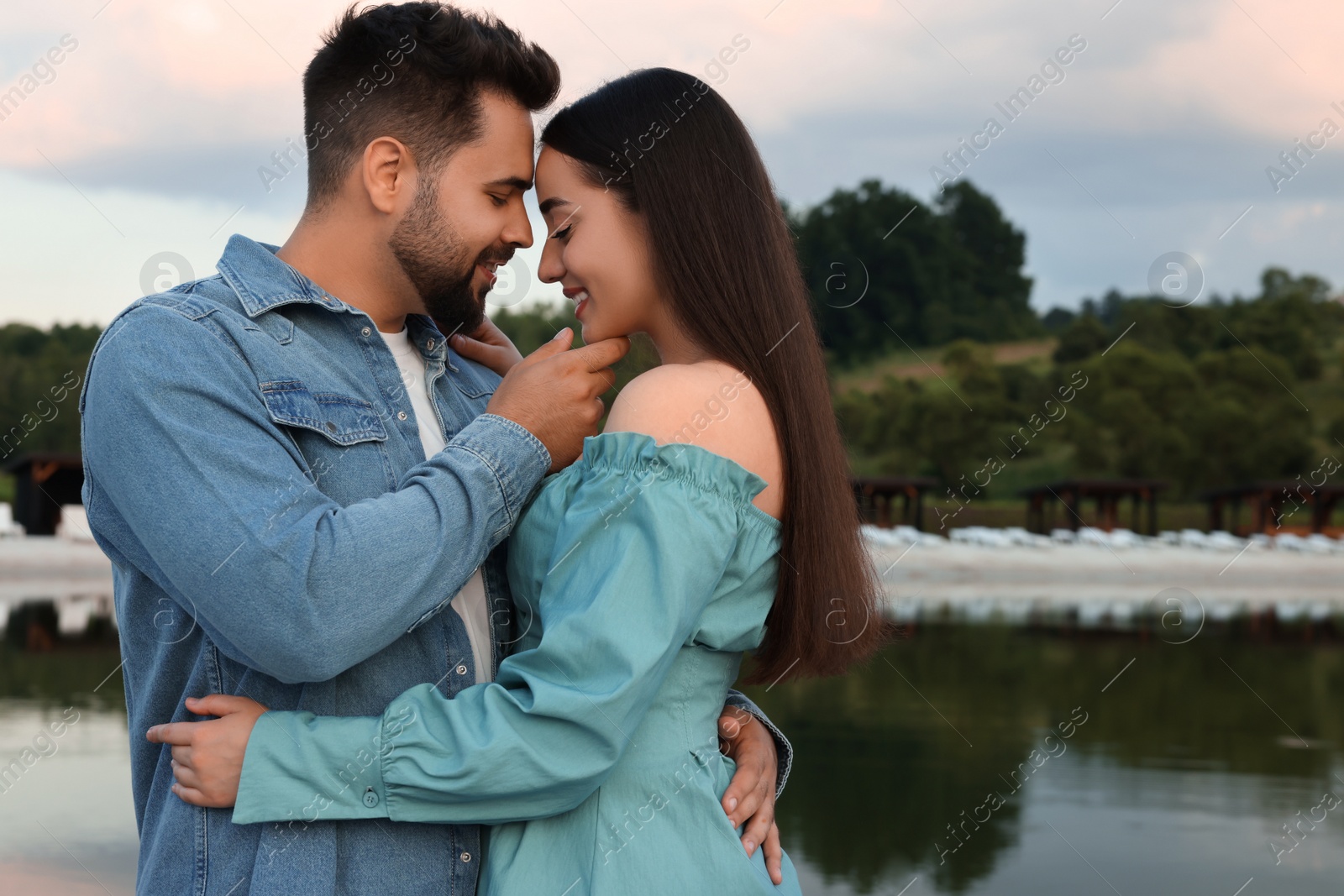 Photo of Romantic date. Beautiful couple spending time together near lake, space for text