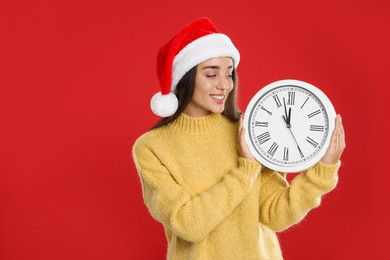 Photo of Woman in Santa hat with clock on red background. New Year countdown