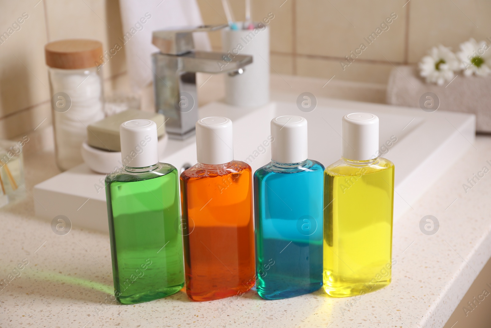 Photo of Fresh mouthwashes in bottles on countertop near sink, closeup