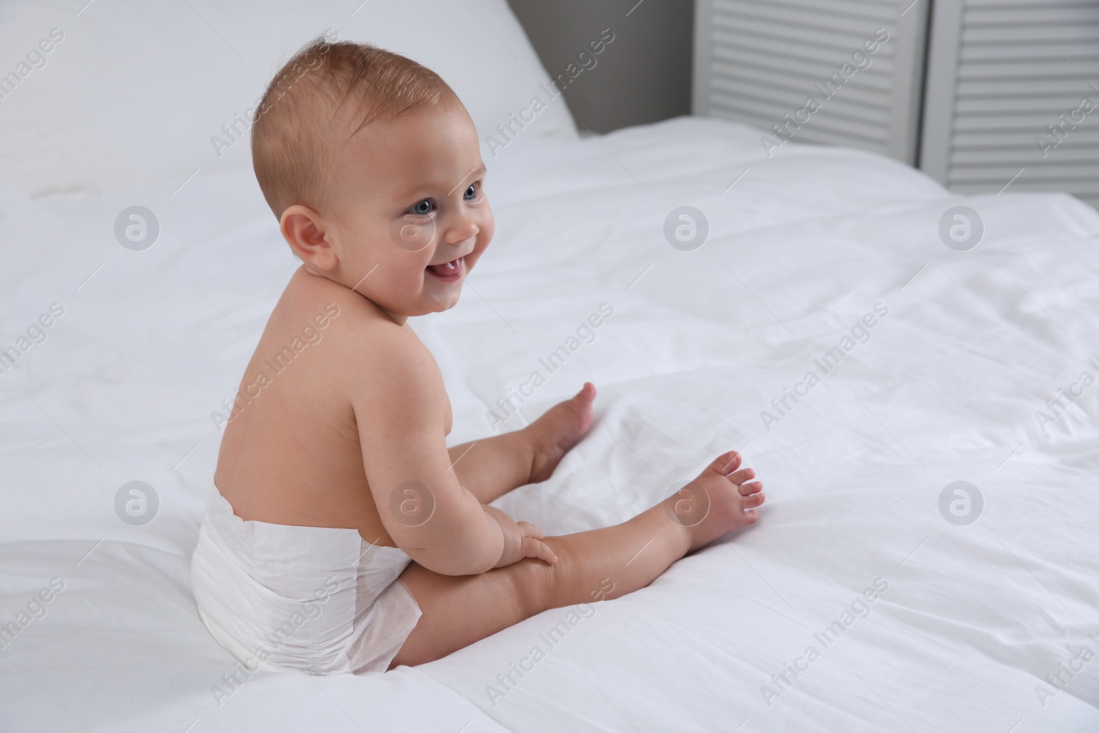 Photo of Cute baby in dry soft diaper on white bed at home