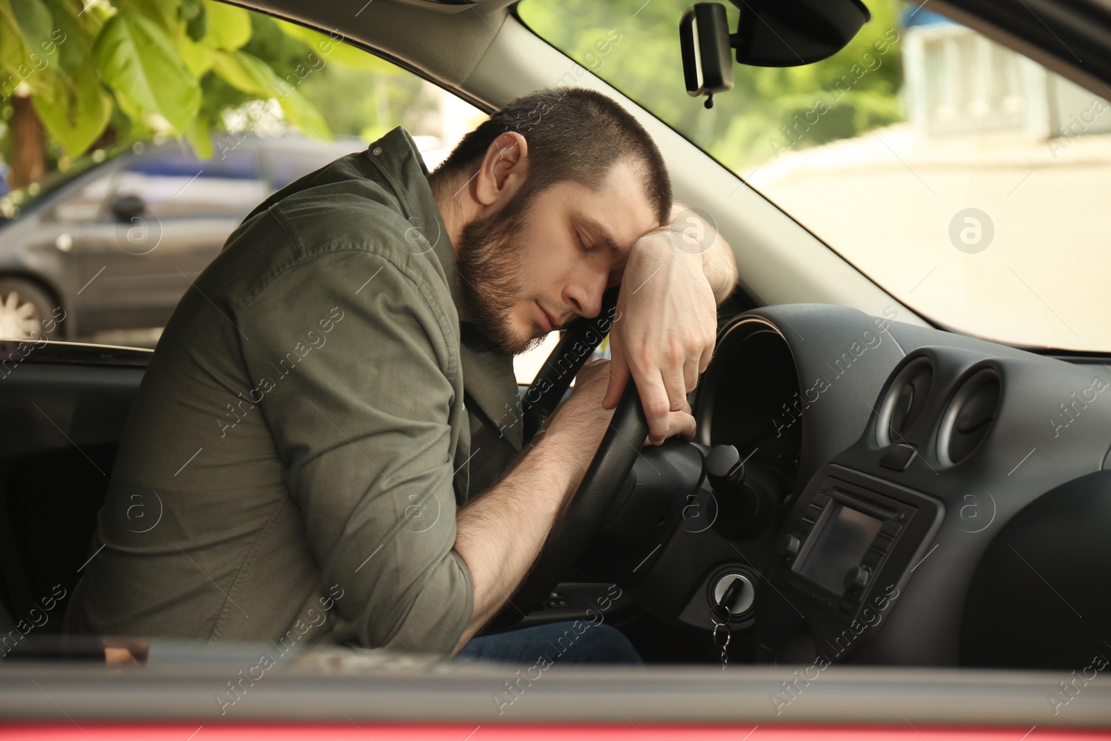 Photo of Tired man sleeping on steering wheel in his car