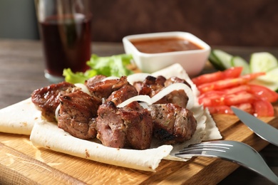 Photo of Wooden board with juicy shish kebab, closeup