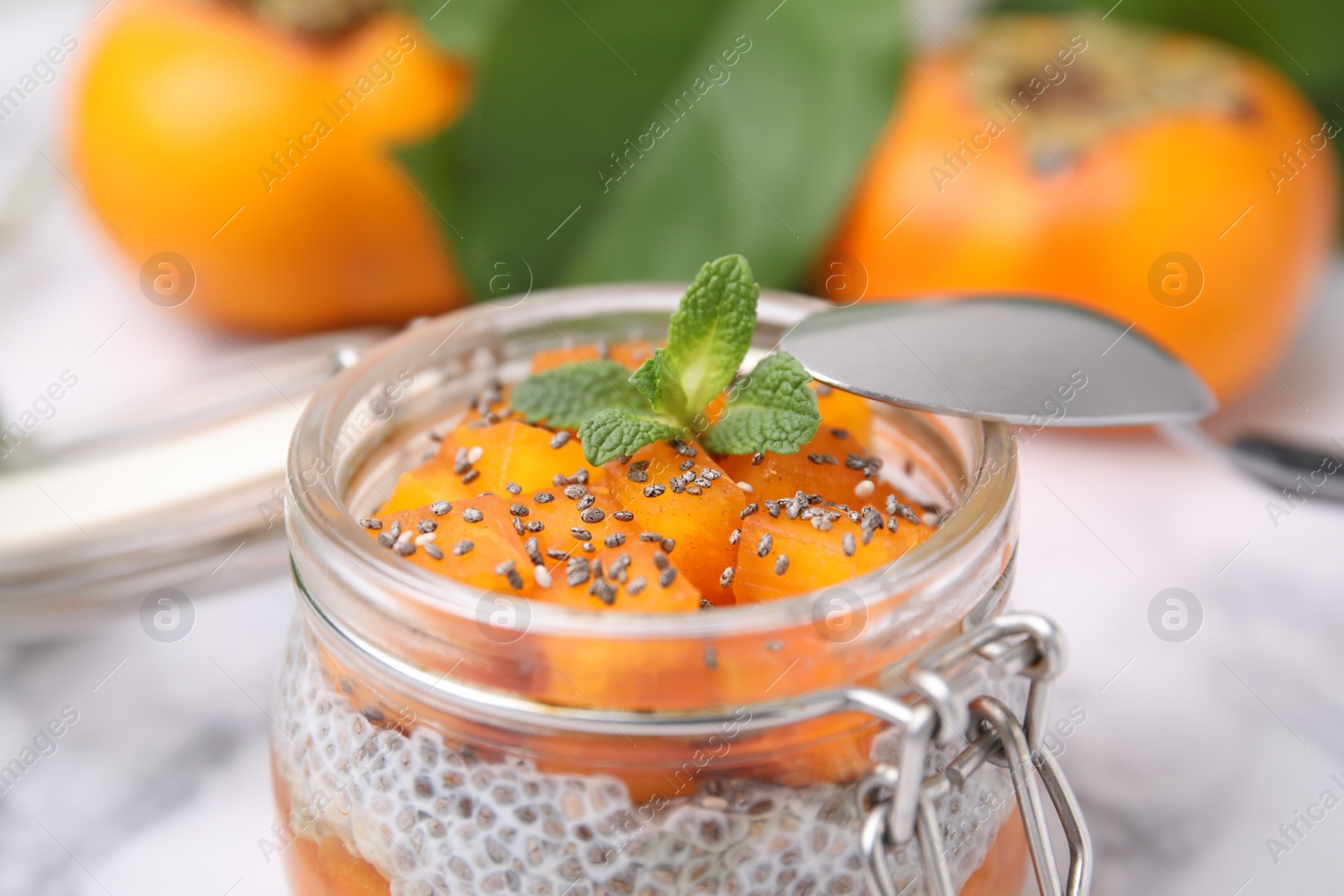 Photo of Delicious dessert with persimmon and chia seeds in jar, closeup