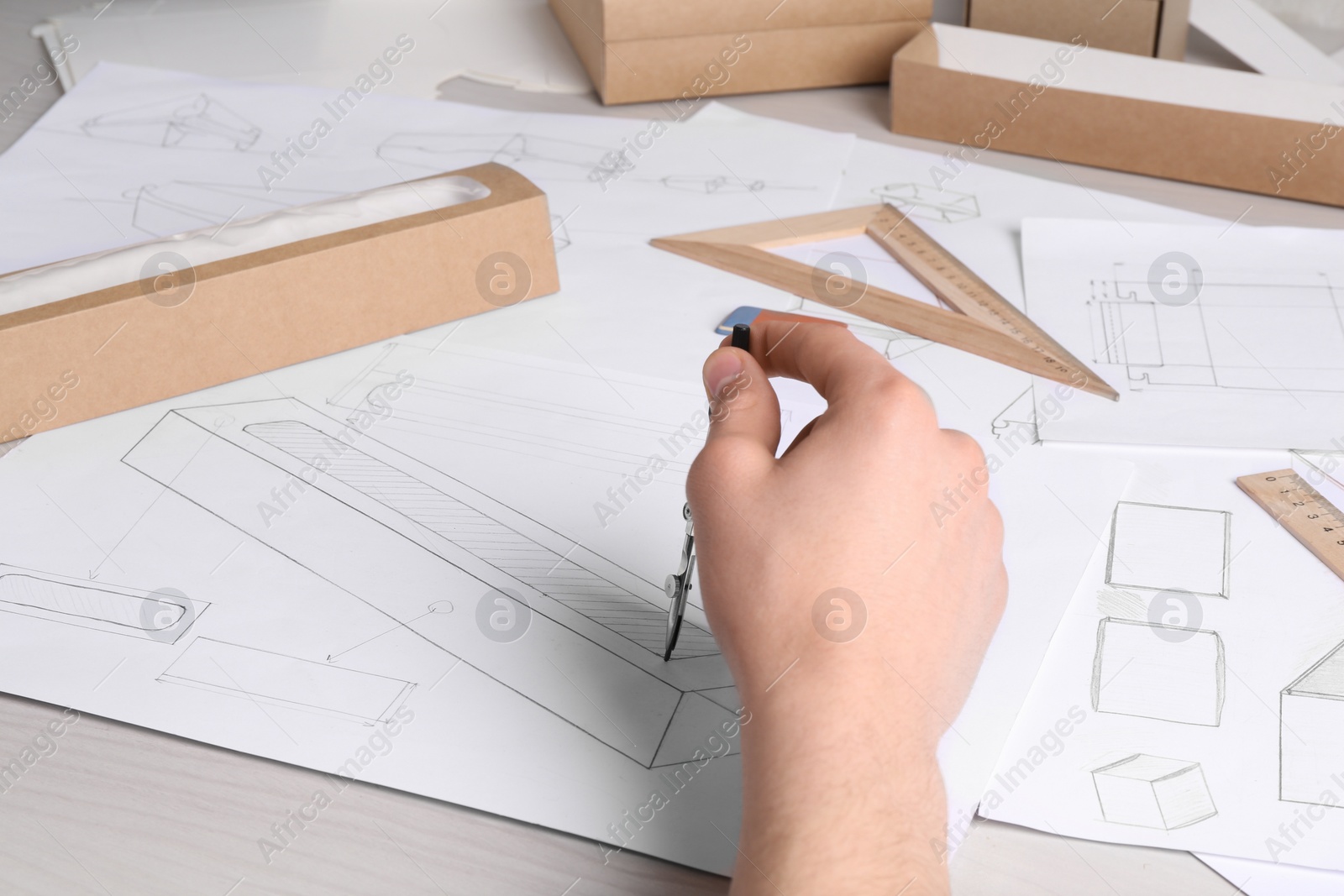 Photo of Man creating packaging design at light wooden table, closeup