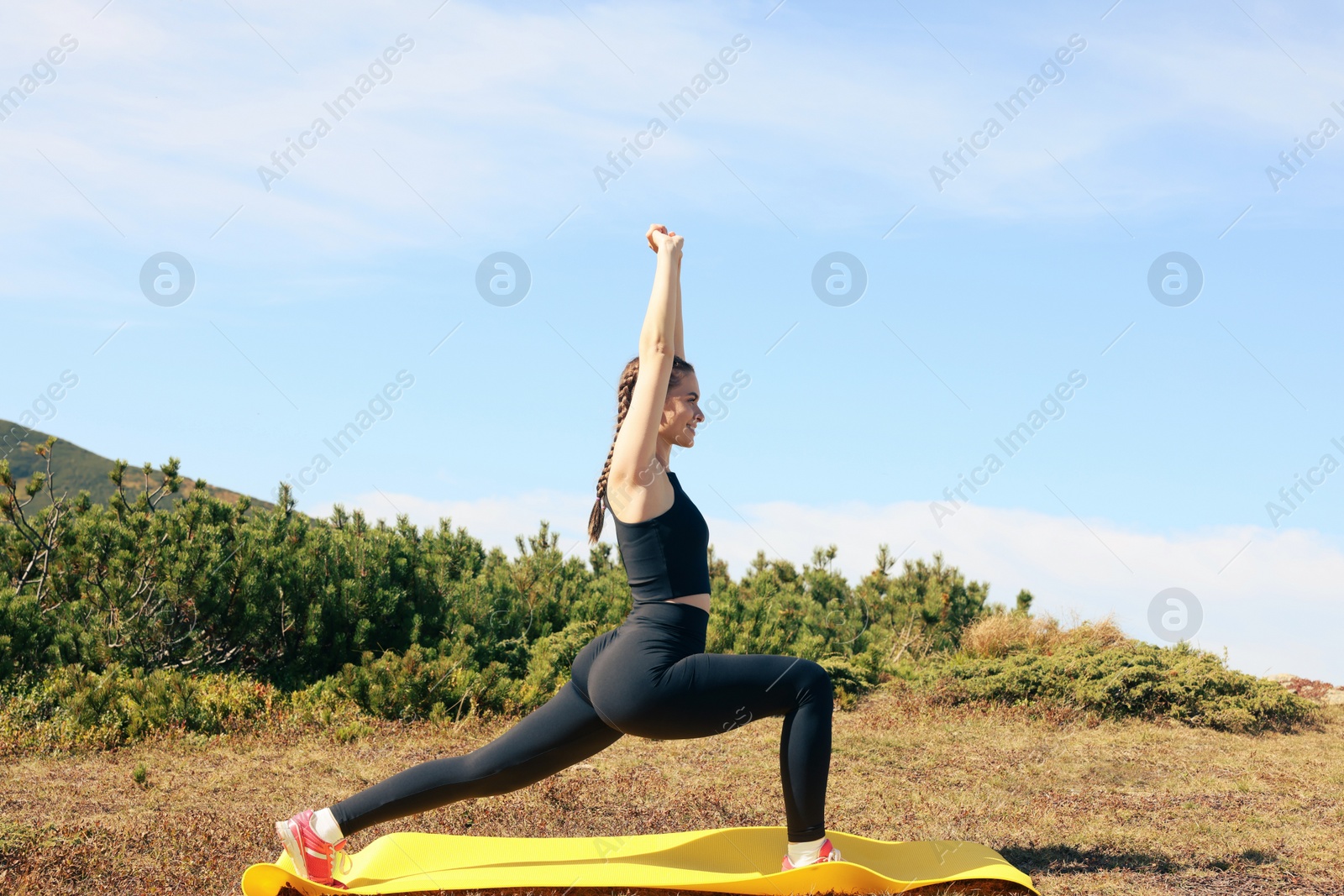 Photo of Beautiful young woman stretching in mountains on summer morning